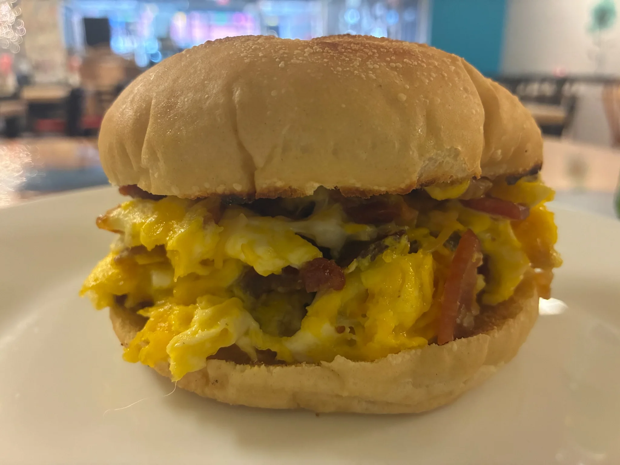 Bacon, egg and cheese breakfast sandwich on a fresh roll served on a white plate at Kat's Cafe & Restaurant.