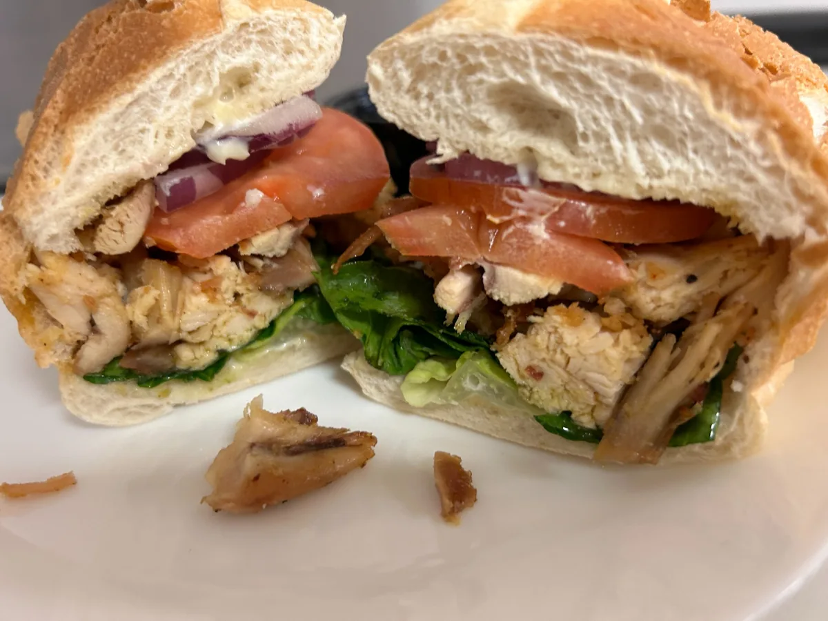 Grilled chicken sub cut in half with pan-grilled seasoned chicken tenders, lettuce, tomato, red onion, and mayo on soft hoagie bread.