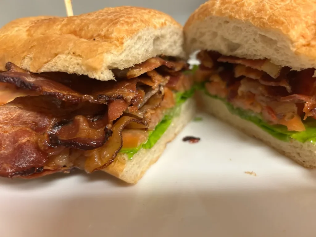 BLT sub cut in half with crispy bacon, lettuce, tomato on toasted hoagie bread.