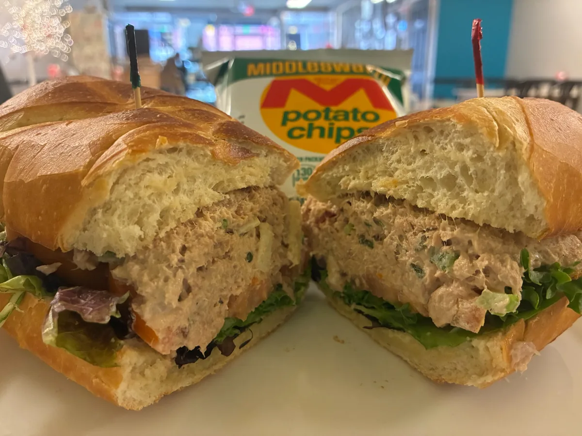 Tuna salad sub cut in half on fresh white hoagie bread with lettuce and tomato, served with chips at Kat's Café & Restaurant.