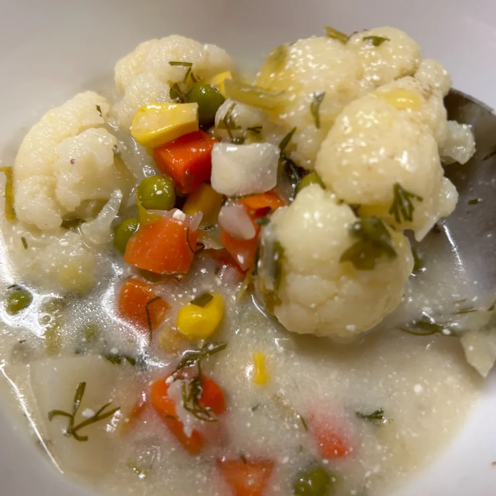 Creamy cauliflower vegetable soup with cauliflower, carrots, peas, corn, and herbs.