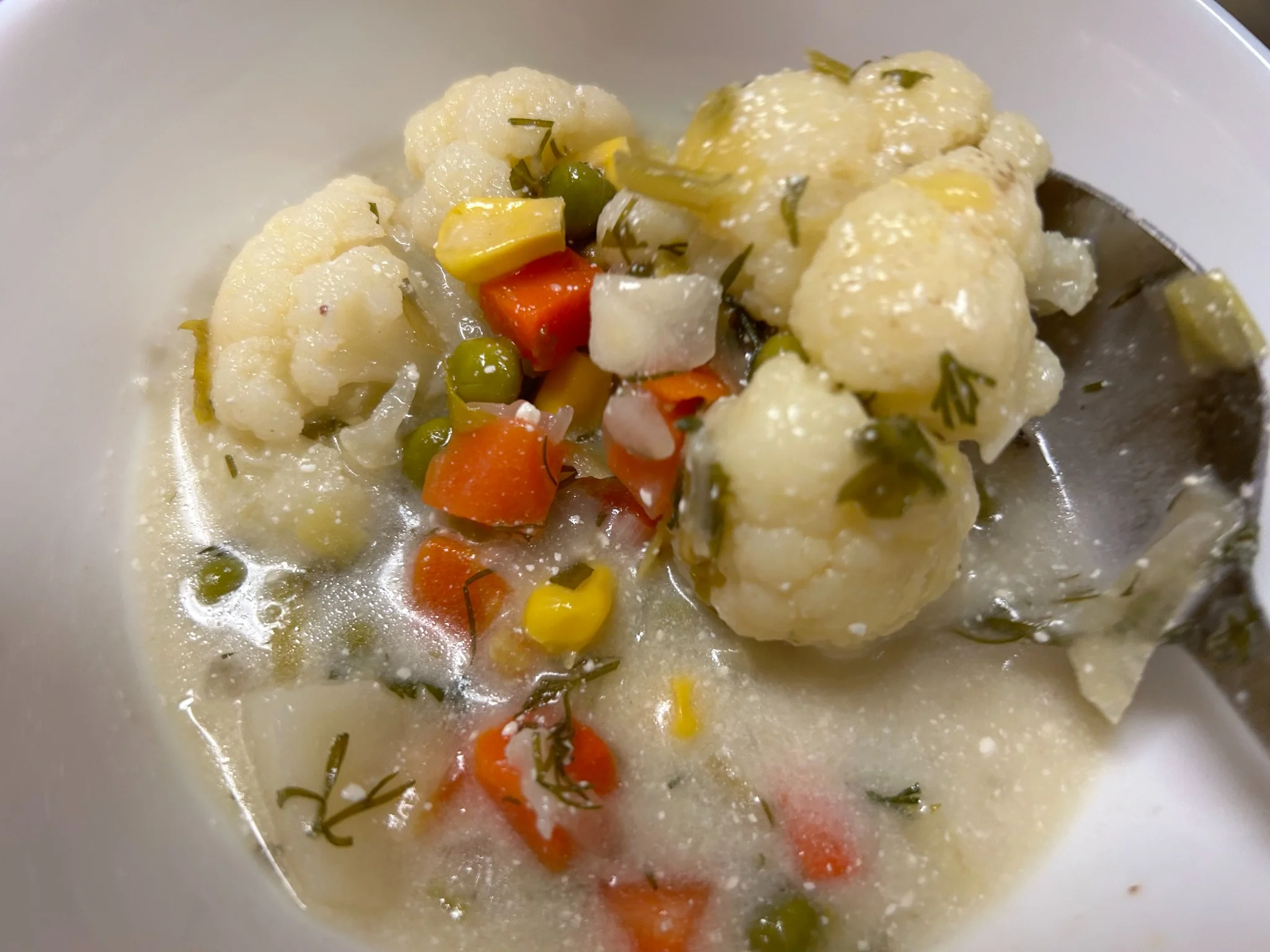 Creamy cauliflower vegetable soup with cauliflower, carrots, peas, corn, and herbs.