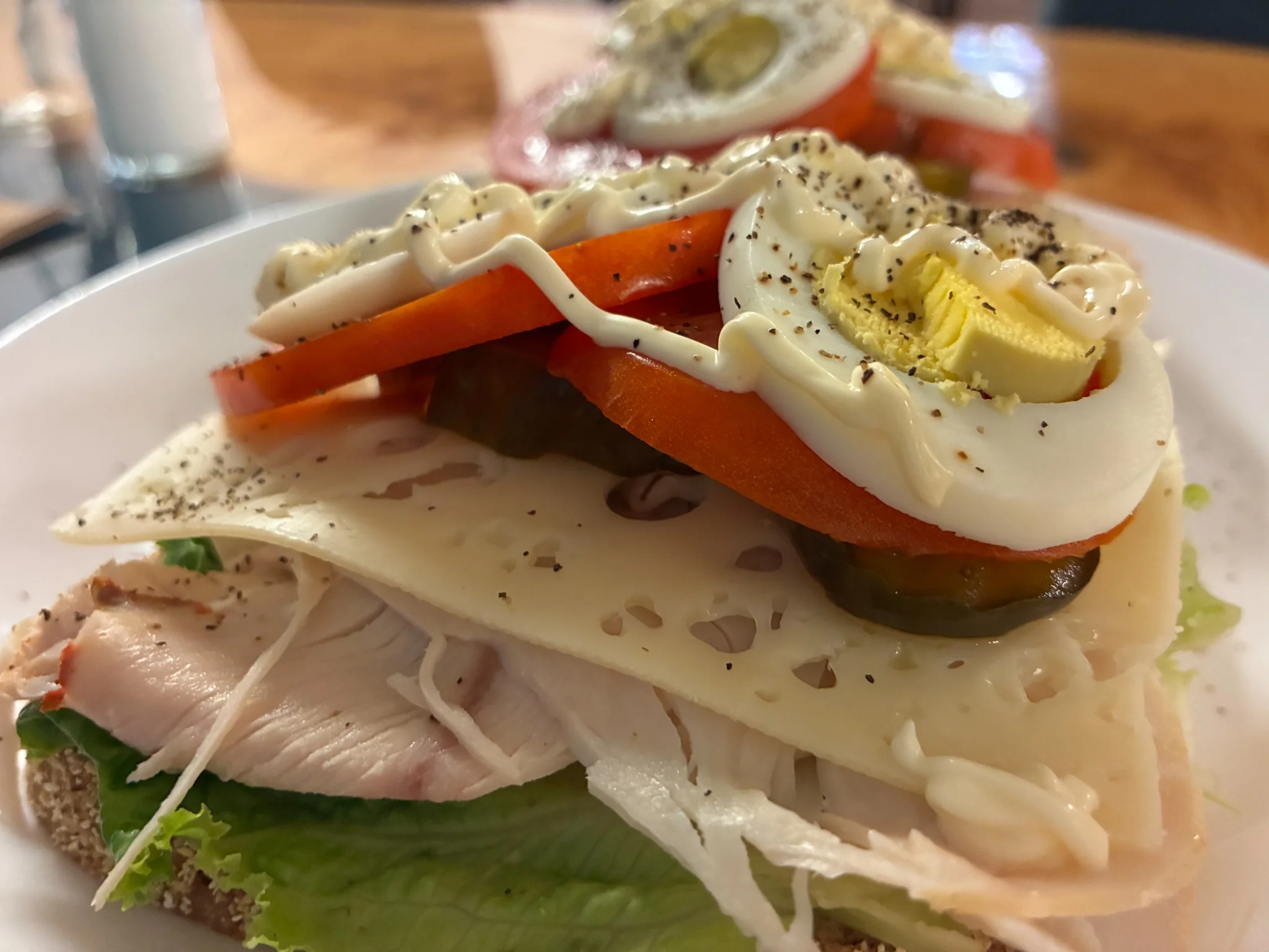 European-style open-faced sandwich with sliced turkey, Swiss cheese, tomato, pickles and hard-boiled egg.