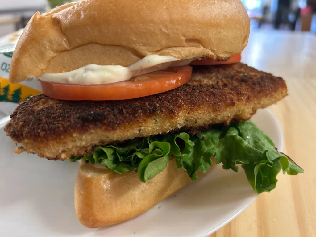 Breaded fish fillet sandwich on a fresh roll with lettuce, tomato and creamy tartar sauce.