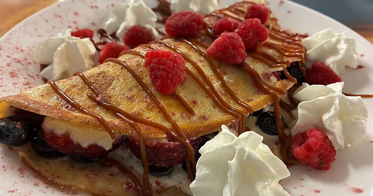 Social share image for Kat’s Café blintzes page showing berry-filled sweet cheese crepes with caramel drizzle and whipped cream.