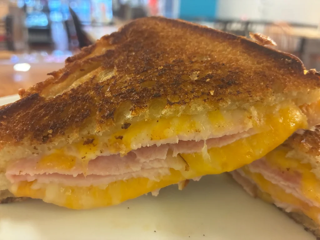 Close-up of a classic grilled ham and cheese sandwich with melted cheese on toasted buttery bread.