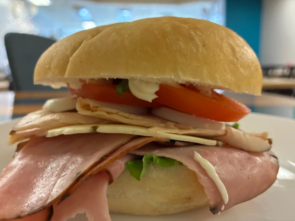 Fresh roll sandwich layered with ham, turkey, hard-boiled egg, tomato, onion and cheese.