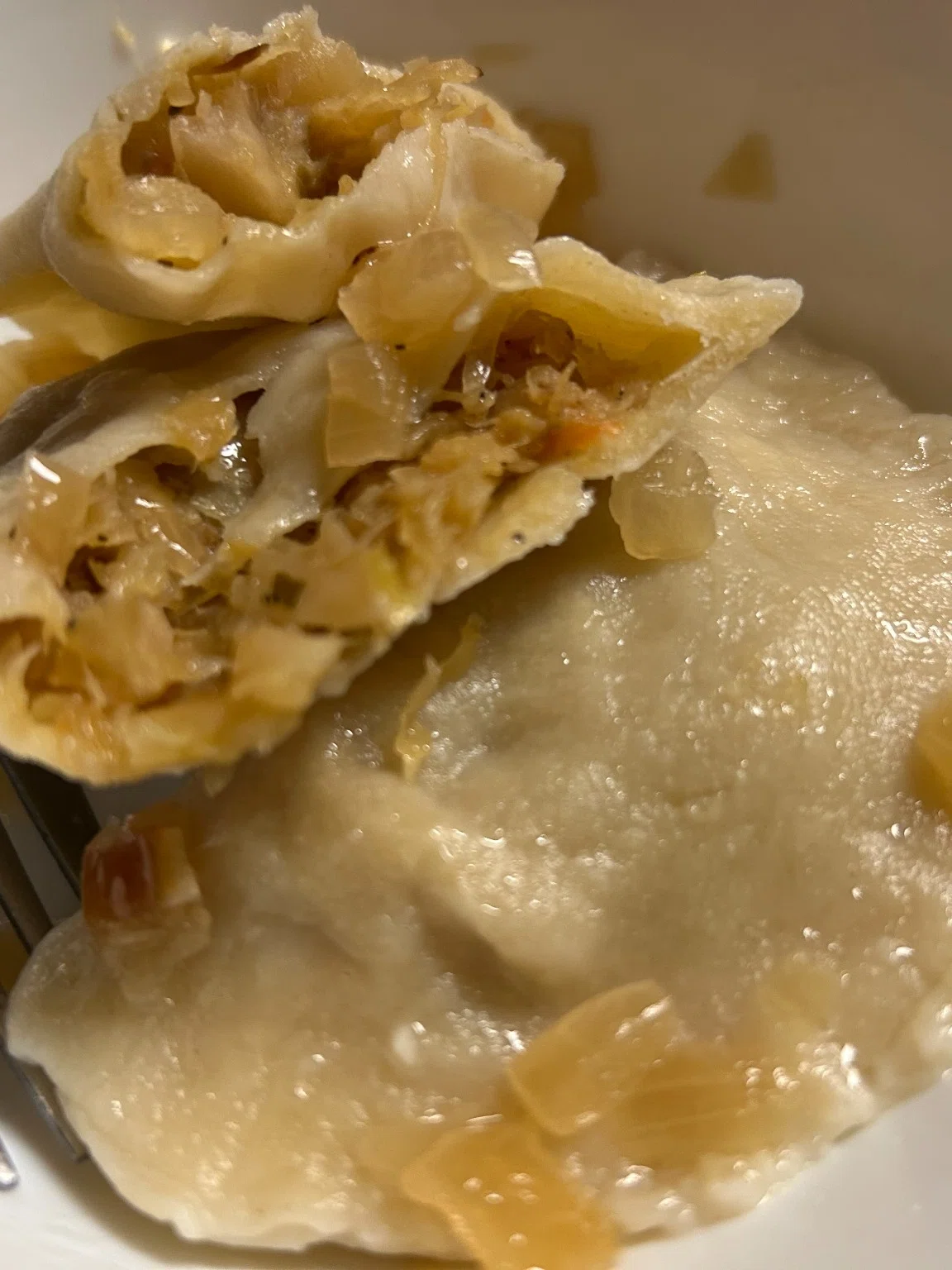 Close-up of a sauerkraut-filled pierogi served with sautéed onions.