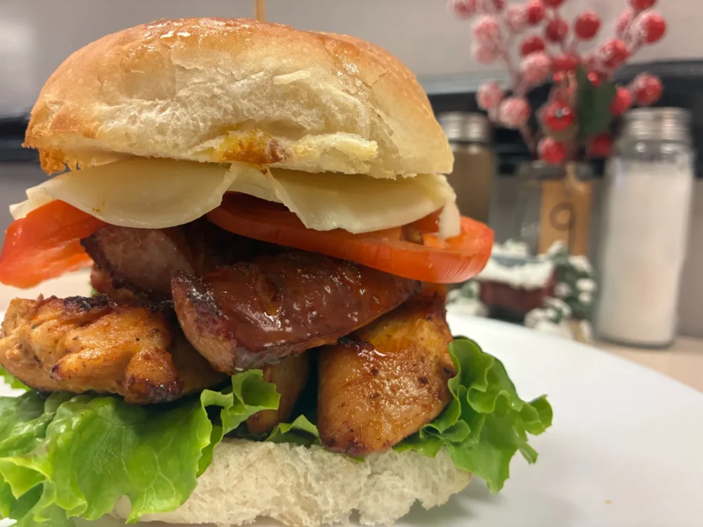 Lunch sandwich with grilled chicken, kielbasa, lettuce, tomato and cheese on a fresh roll.