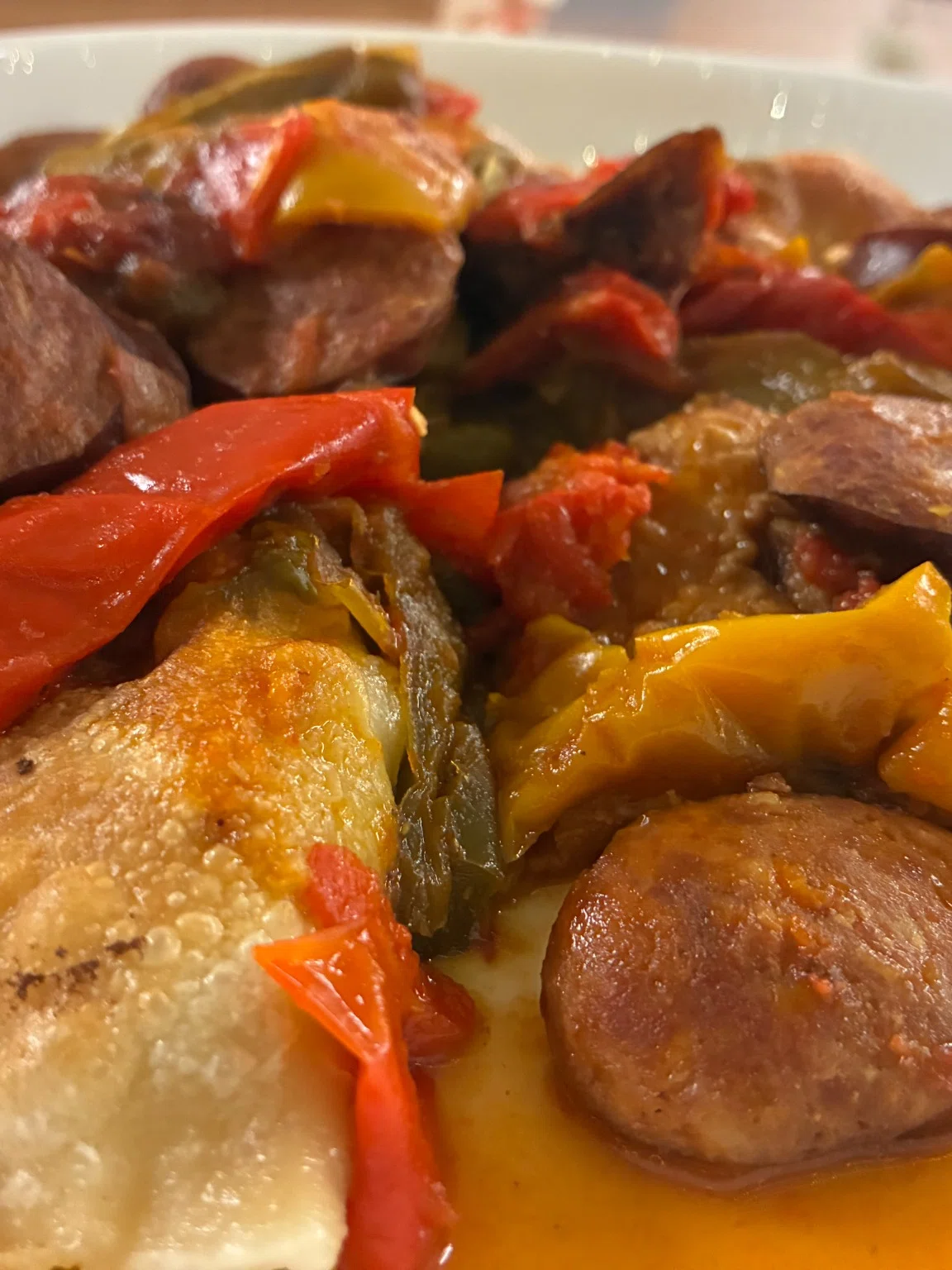 Pierogi meal having potato-cheese pierogis topped with letcho peppers and sliced kielbasa in a light tomato sauce.
