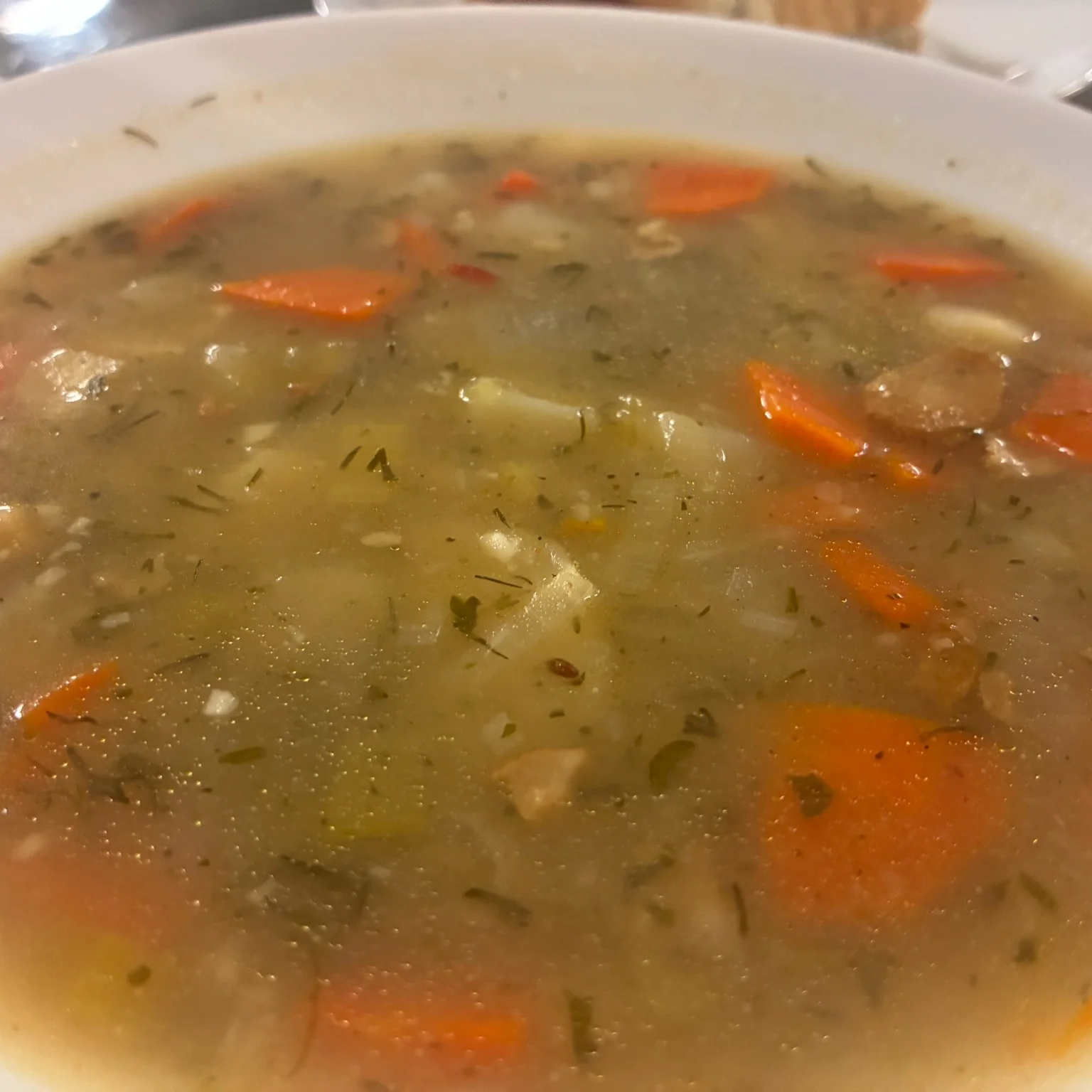 Potato leek soup with diced potatoes, carrots, herbs, and leeks in a light broth.