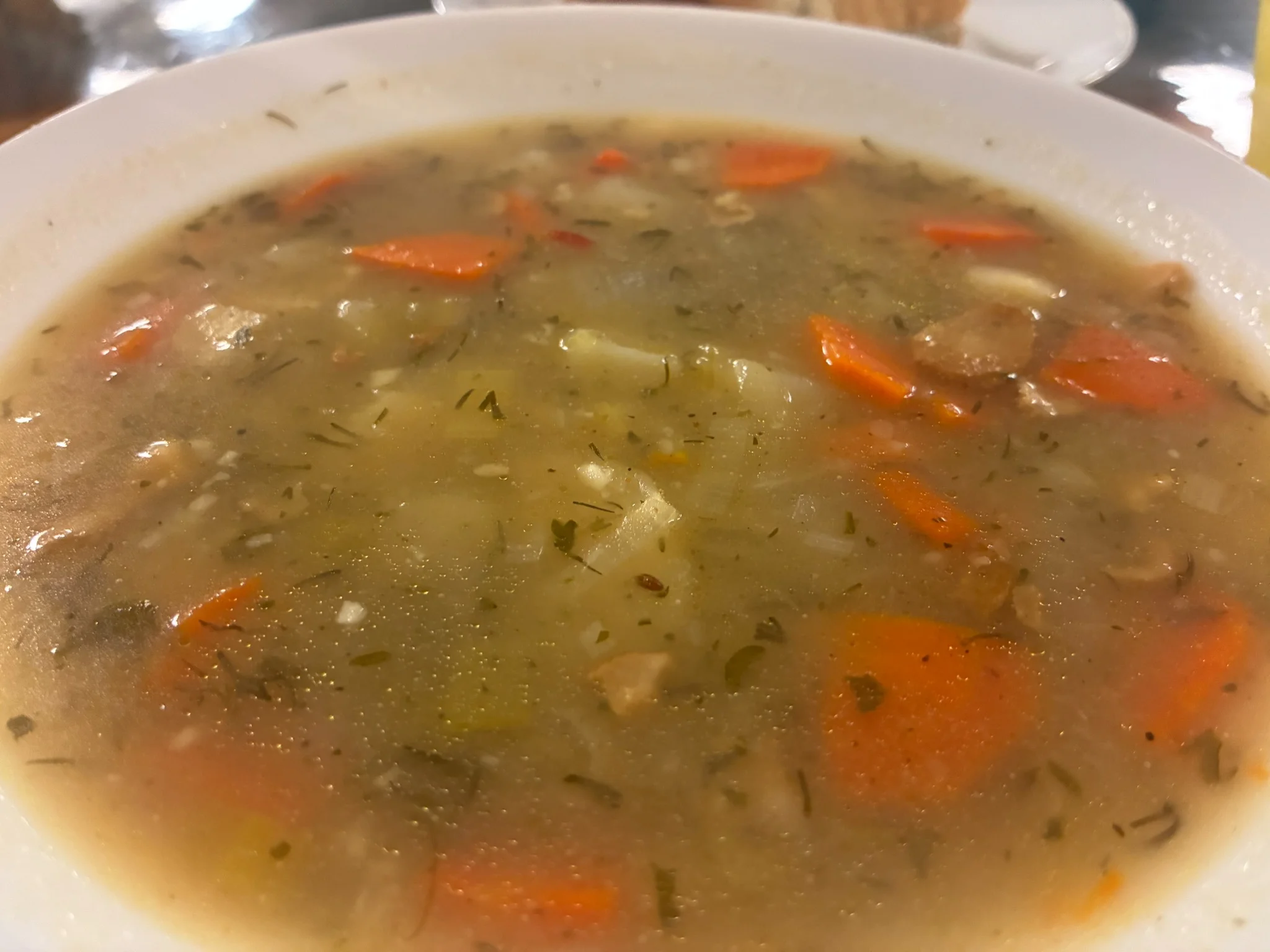 Potato leek soup with diced potatoes, carrots, herbs, and leeks in a light broth.