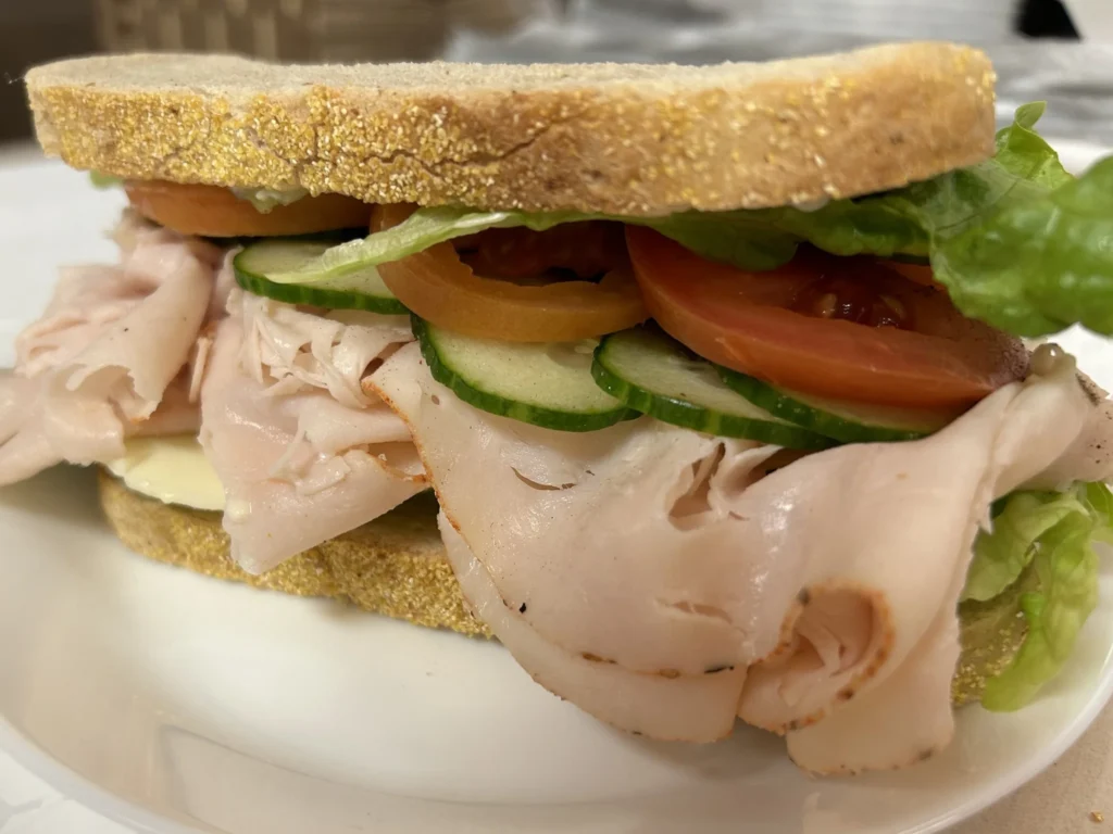Turkey sandwich on rye bread with lettuce, tomato and cucumber.