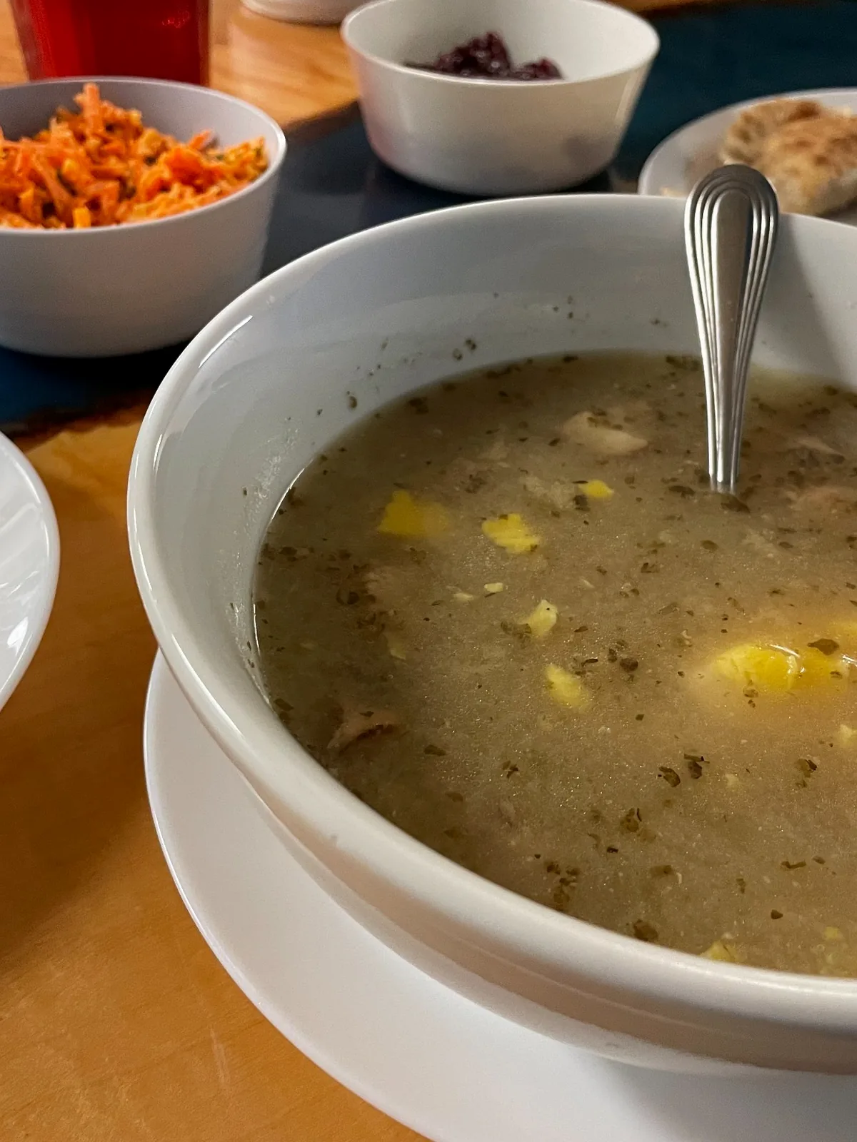 Bowl of Polish żurek soup with fried mashed potatoes, hardboiled egg, white kielbasa, and herbs alongside other menu items. 