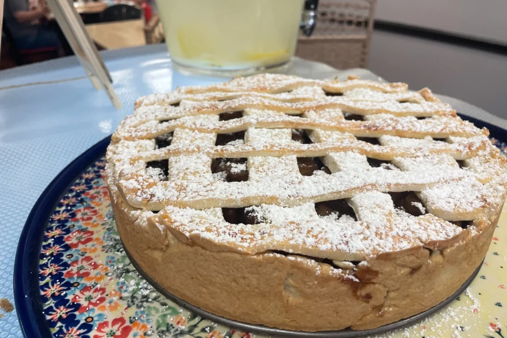 Apple nut country-style pie with a powdered sugar lattice crust, shown whole on a decorative platter.