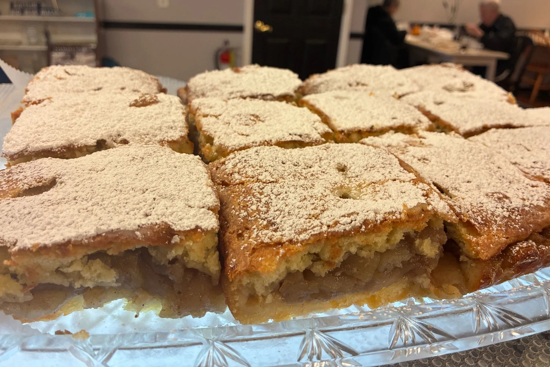 Squares of Polish apple szarlotka layered with spiced apples and finished with powdered sugar.