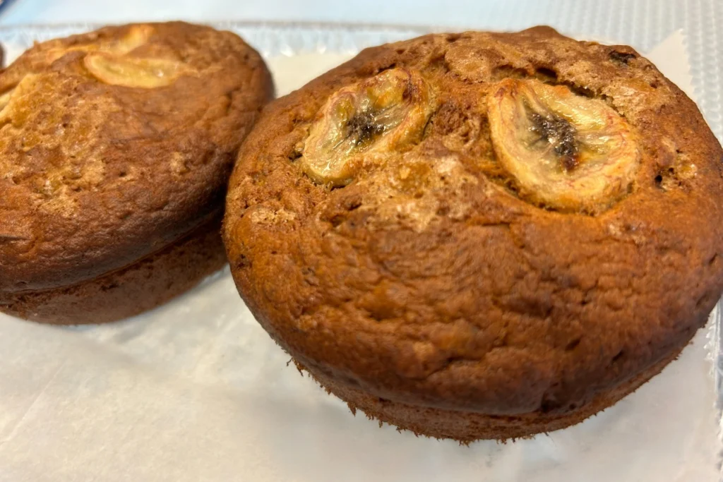 Banana bread muffin mini cakes topped with baked banana slices and a rich golden-brown crust.