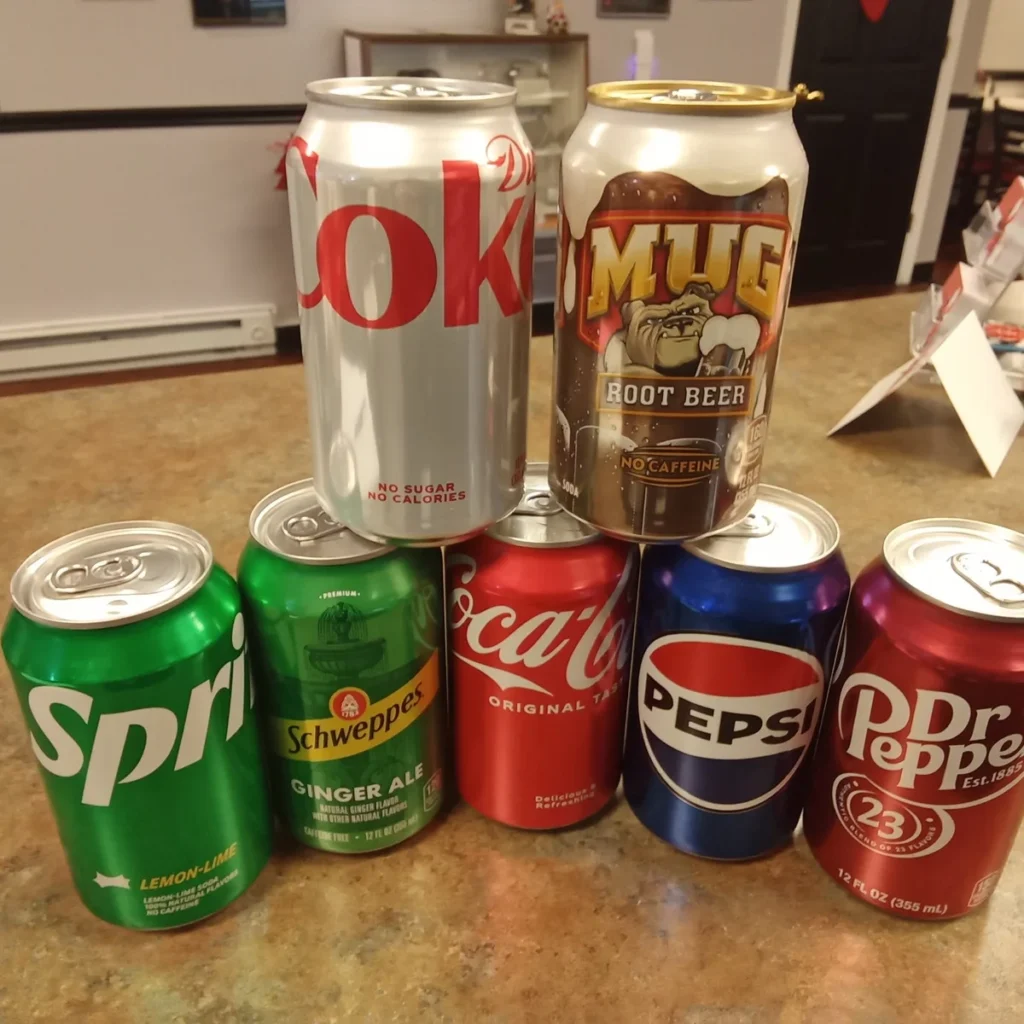 Selection of canned soft drinks, including Sprite, Coke, Pepsi, Dr Pepper, Diet Coke, Ginger Ale, and Root Beer.