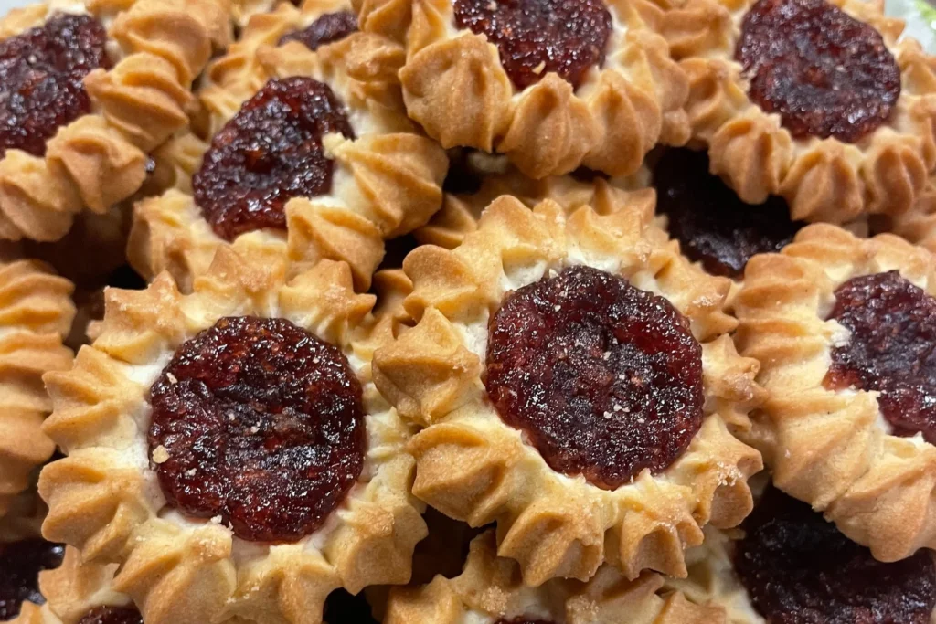 Cherry tart cookies with piped golden pastry and glossy cherry centers arranged on a platter.