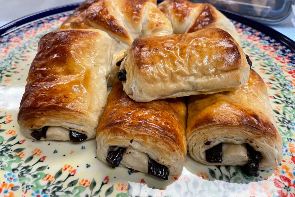 Chocolate-filled croissants and pain au chocolat with flaky golden pastry arranged on a floral platter.