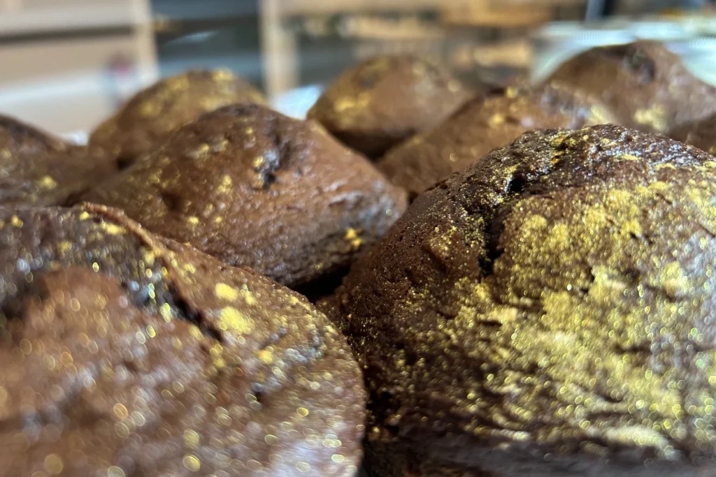 Rich chocolate mini cakes dusted with edible gold in Kat's dessert case.