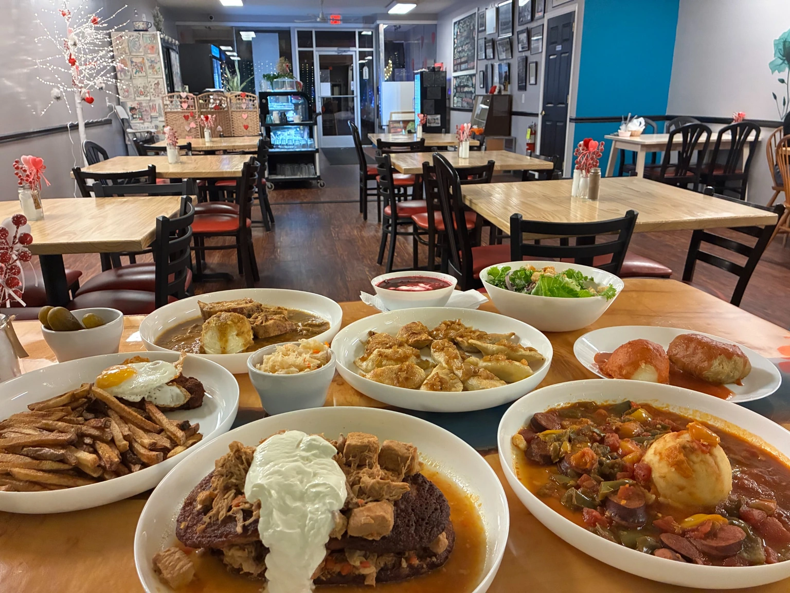 Table filled with Kat's Café & Restaurant comfort food dishes in the foreground with the dining room and tables in the background.