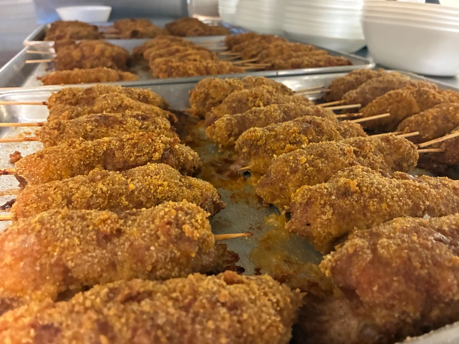 Breaded ground city chicken skewers baking on sheet pans for a large Kat’s Café & Restaurant catering order.