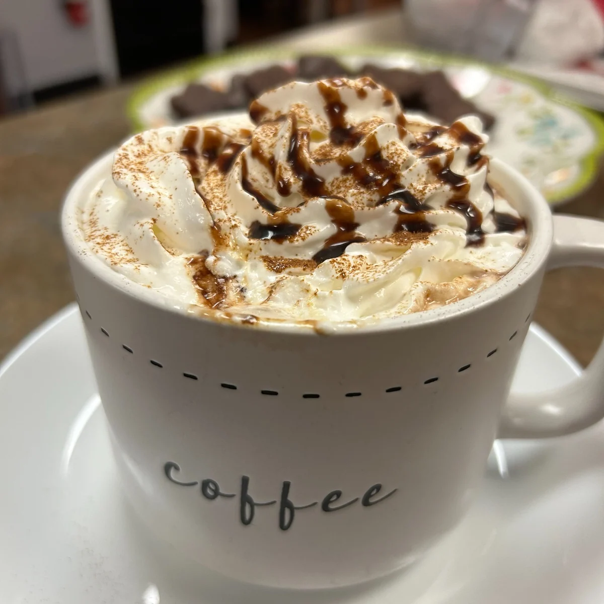 Mocha coffee topped with whipped cream, chocolate drizzle, and caramel in a white cup at Kat's Café & Restaurant.