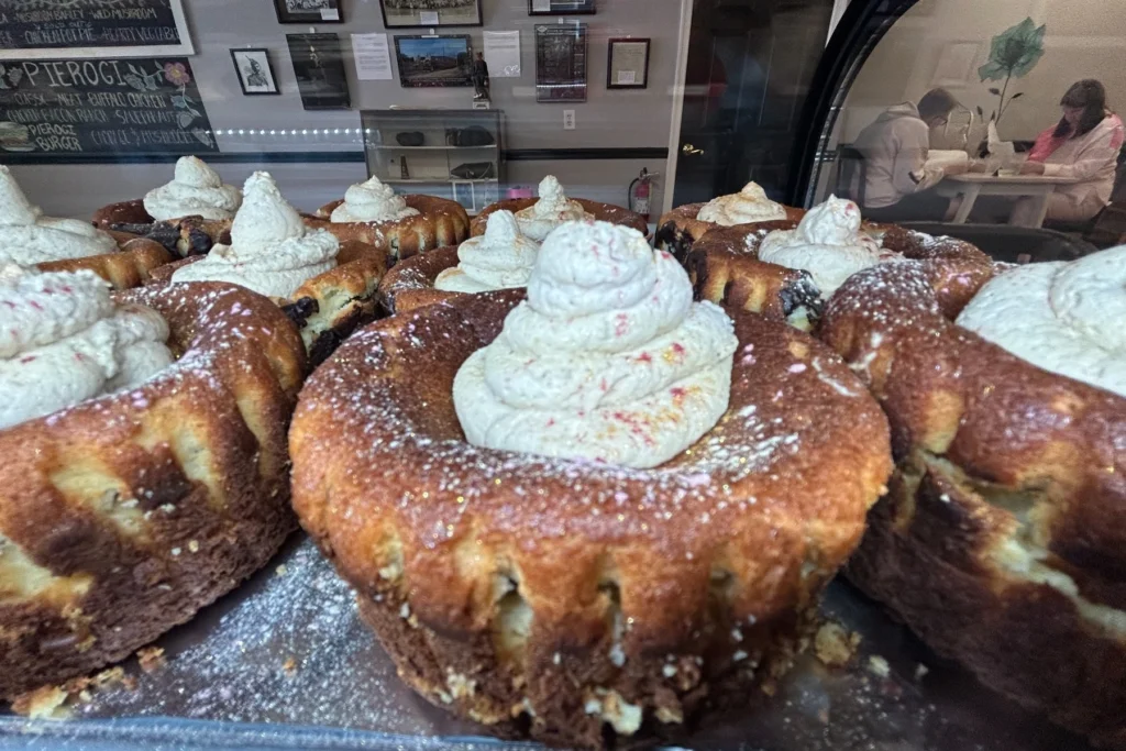 Assorted mini cakes topped with piped cream in Kat's dessert case.