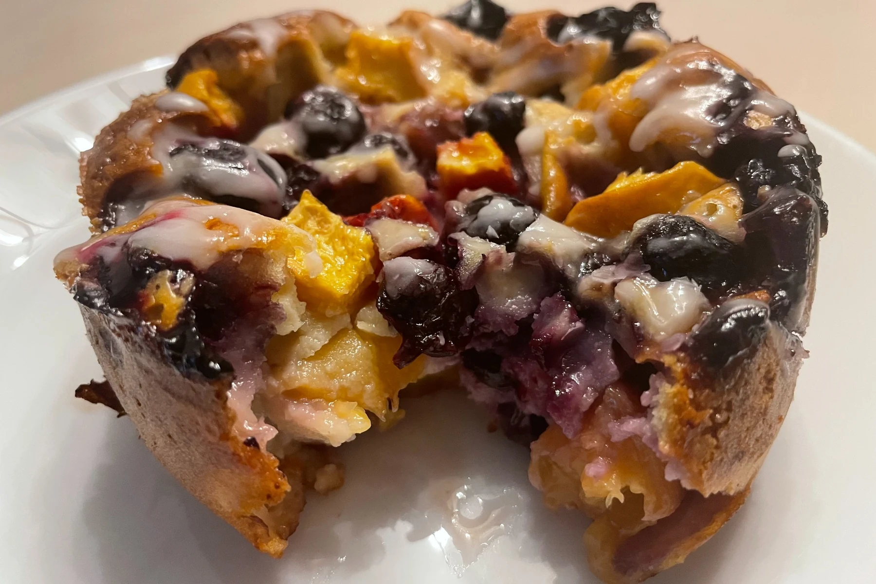 Individual peach and berry mini cake packed with fruit and finished with a light glaze.