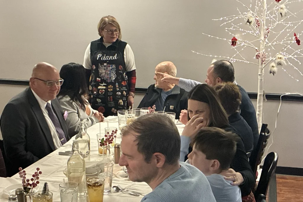 Chef Kat speaking to guests seated at a shared table during the Christmas Eve Holy Supper at Kat’s Café & Restaurant.