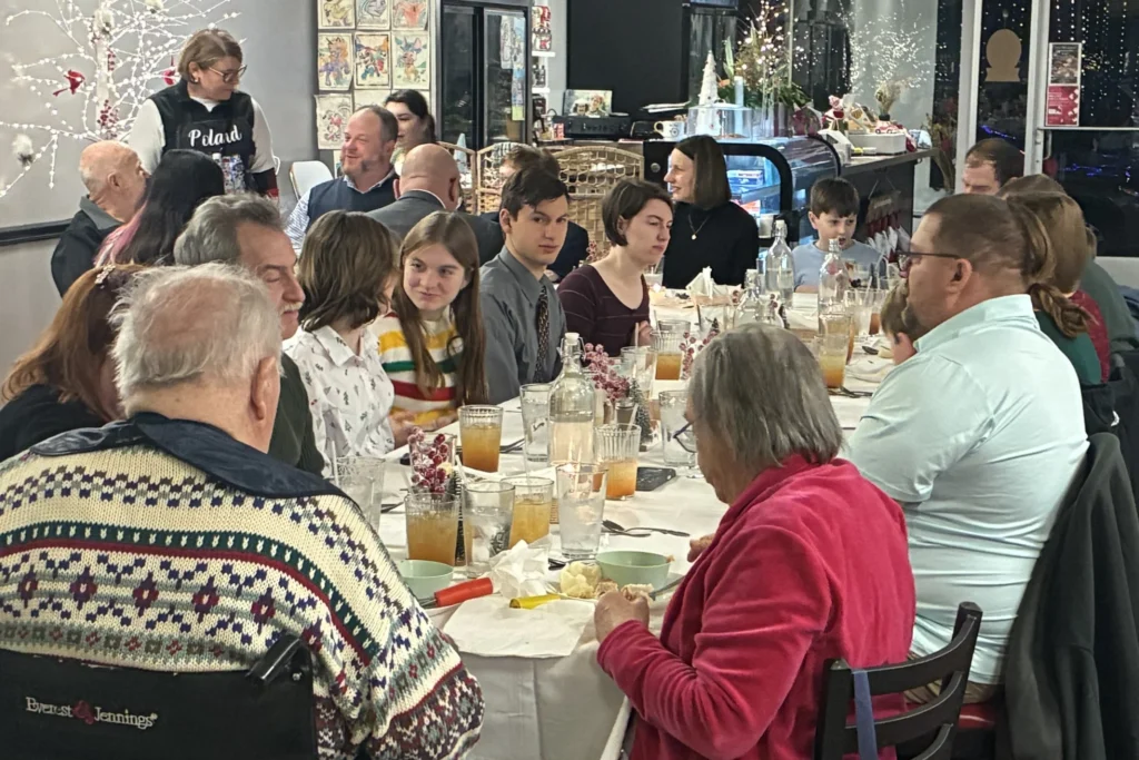 A full table of guests enjoying Kat’s Café & Restaurant's Christmas Eve Holy Supper in a festive dining room.