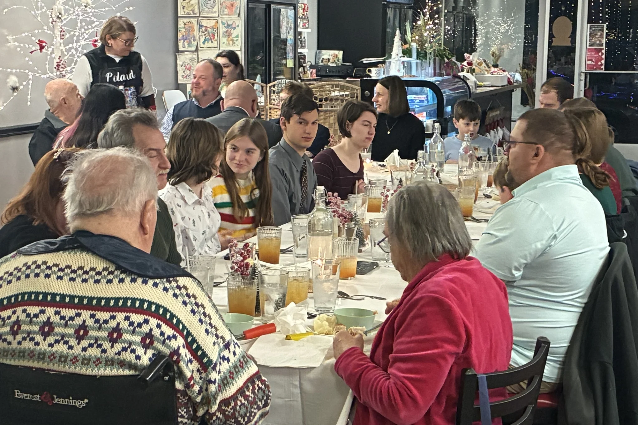 A full table of guests enjoying Kat’s Café & Restaurant's Christmas Eve Holy Supper in a festive dining room.