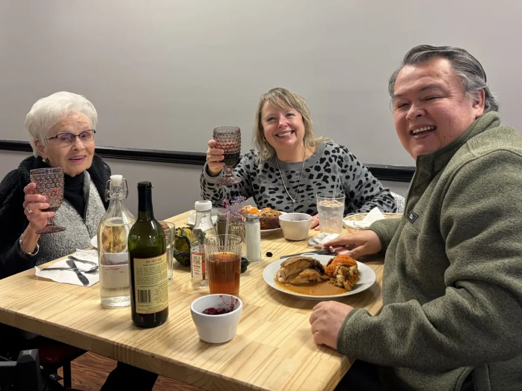 Three guests smiling over a meal and wine at Kat’s Café & Restaurant.