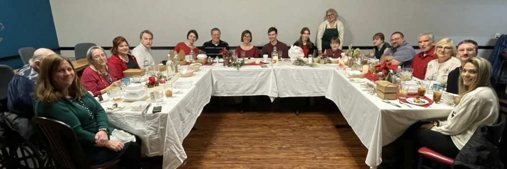 Guests seated around U-shaped tables for a group photo during Kat’s Café & Restaurant’s Polish Holy Supper, with Chef Kat standing in the background.
