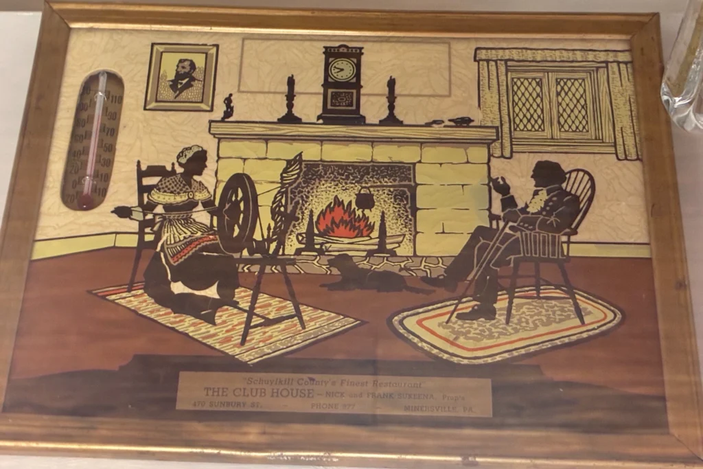 Framed vintage artwork for "The Club House" restaurant on display at Kat’s Café & Restaurant.