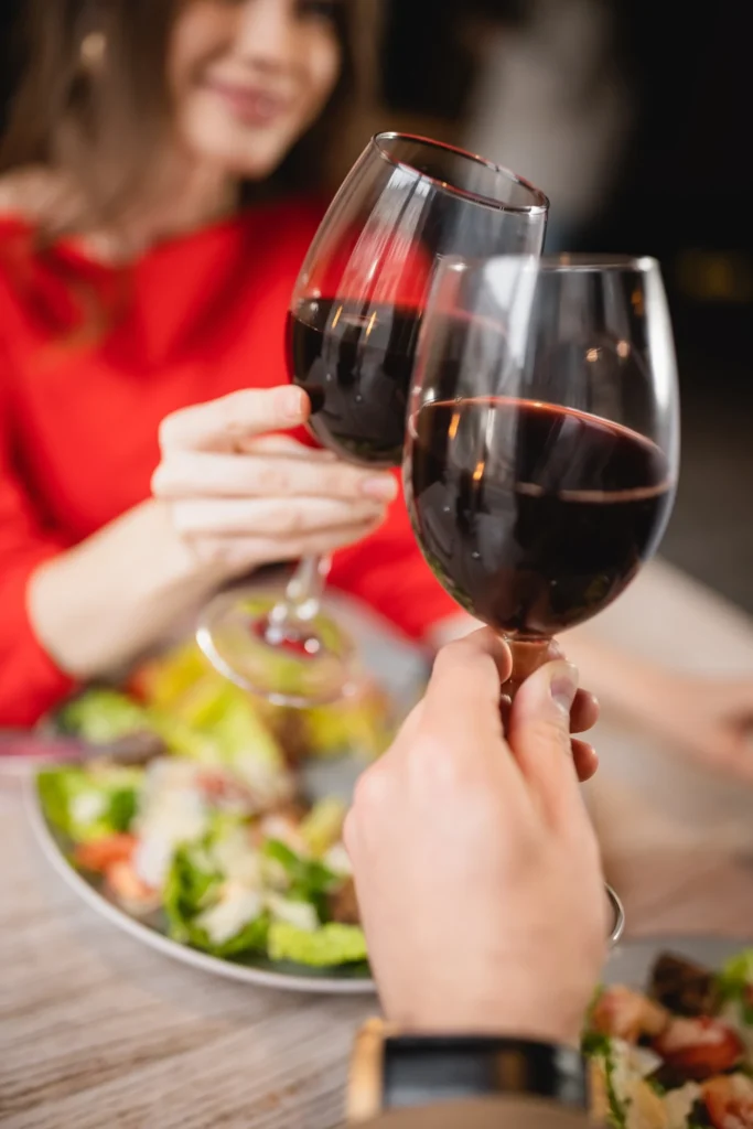 Two people toast with wine glasses over a meal during a romantic dinner.
