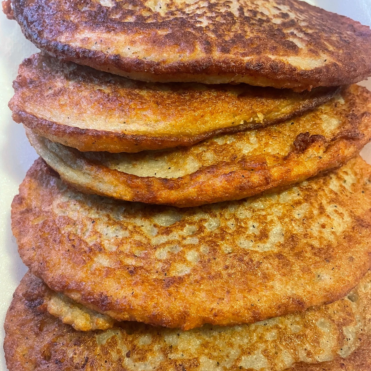 Stack of golden potato blinis (bleenies) on a white plate at Kat’s Café & Restaurant.
