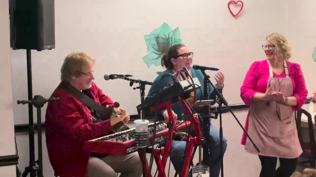 Musicians perform live while Chef Kat smiles beside them during a Valentine’s event at Kat’s Café & Restaurant.