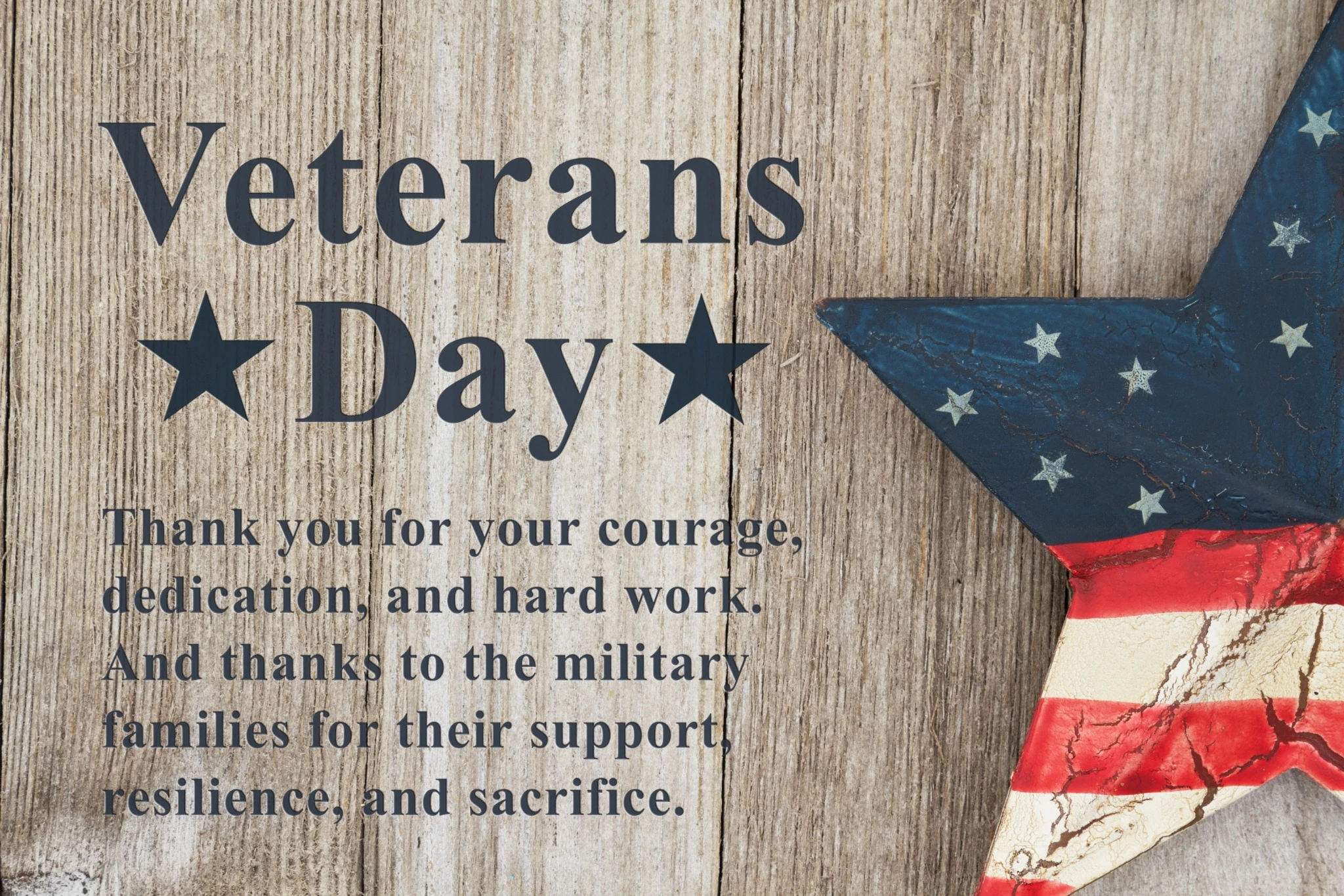 Veterans Day thank-you message on a rustic wood background with a patriotic star decoration.