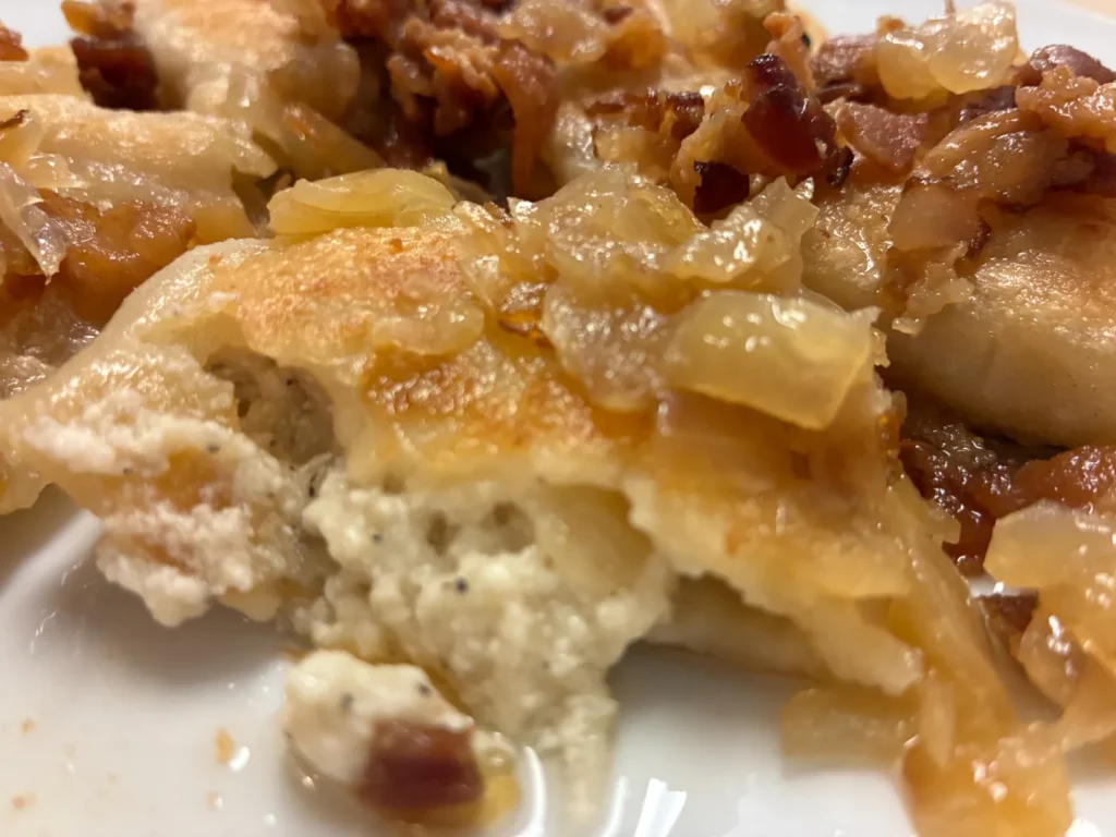 Close-up of a potato and cheese pierogi cut open and topped with onions and crumbled bacon at Kat’s Café & Restaurant.