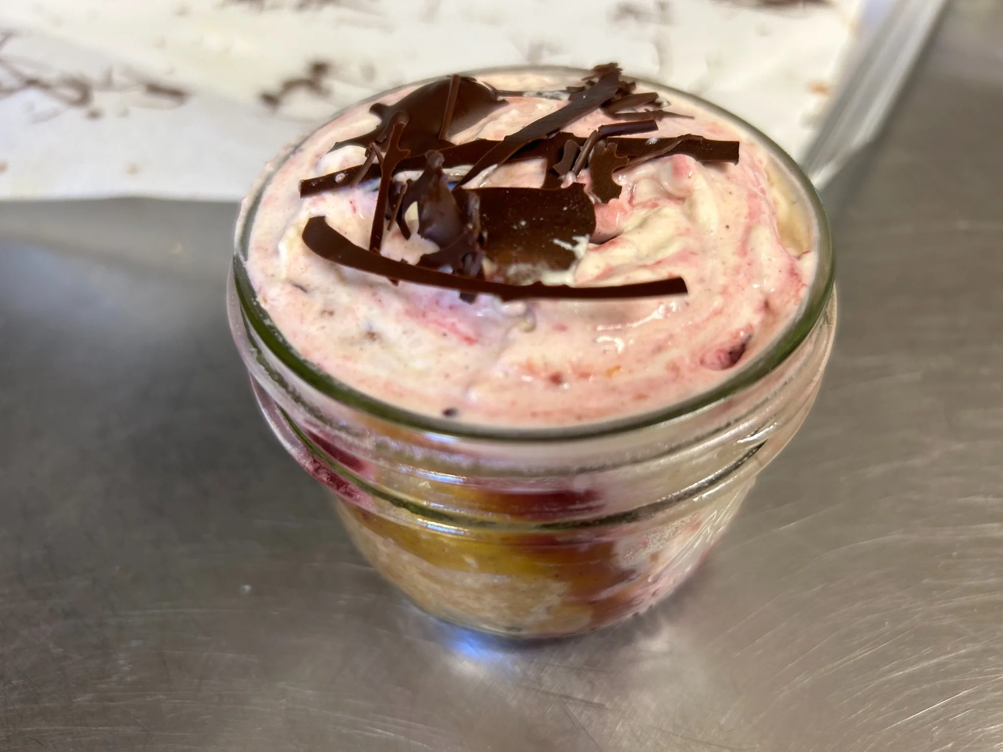 Layered berry cream dessert in a small mason jar topped with cream and dark chocolate shavings at Kat’s Café & Restaurant.