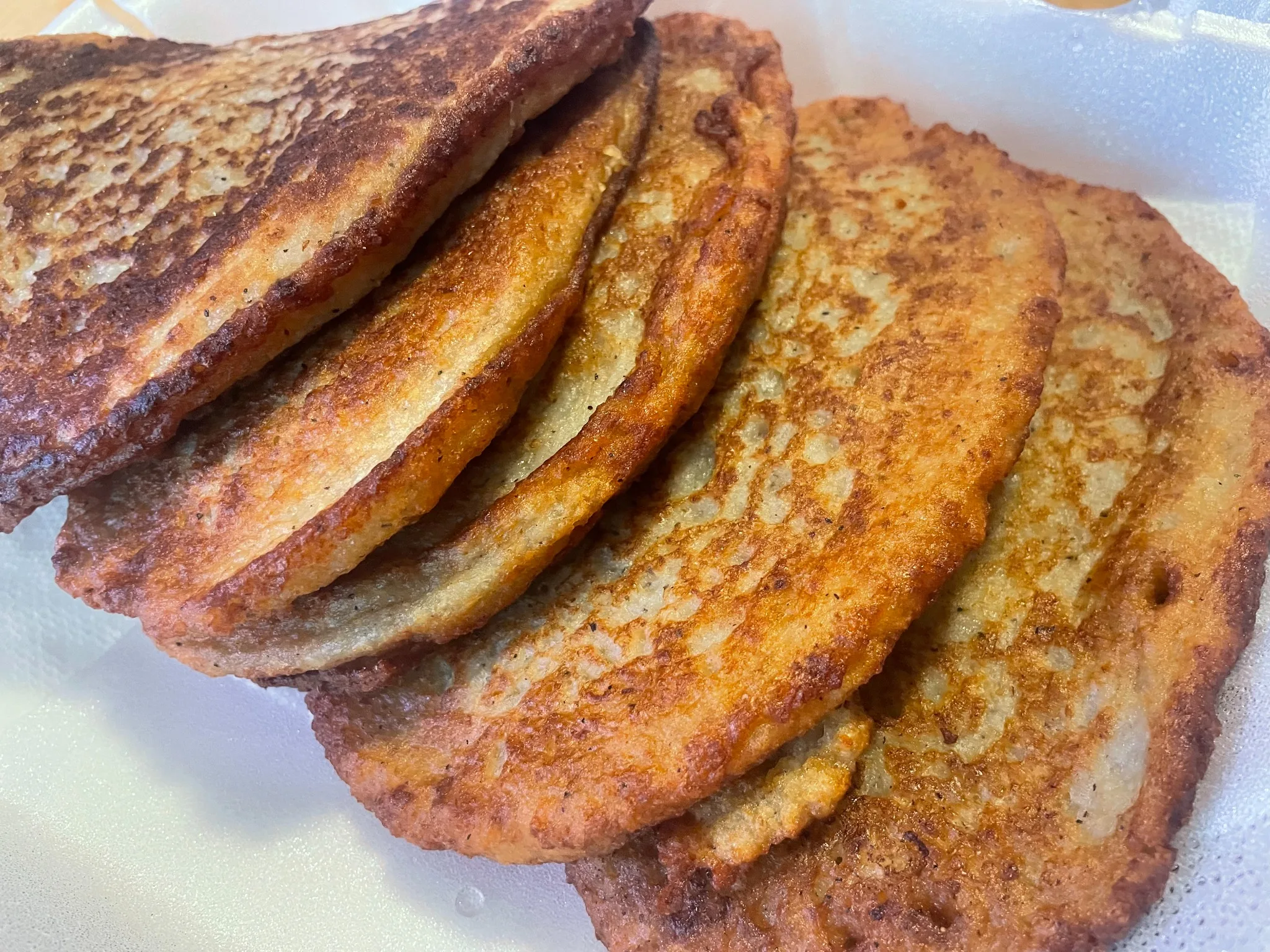 Overhead view of golden potato pancake bleenies served with a cup of sour cream at Kat’s Café & Restaurant.