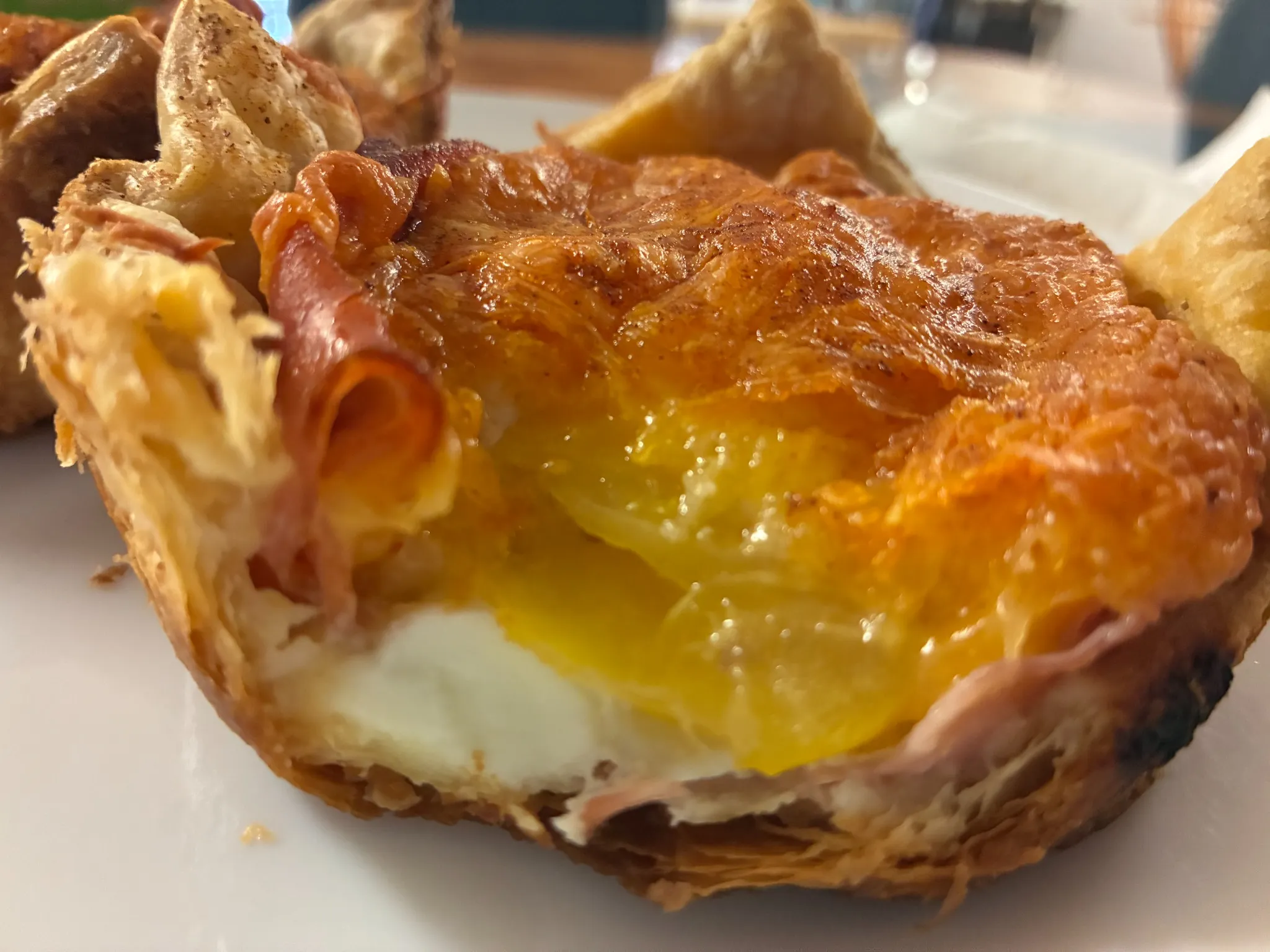 Fresh baked croissant filled with ham, fried egg, and melted cheese topping, served on a white plate at Kat’s Café & Restaurant.