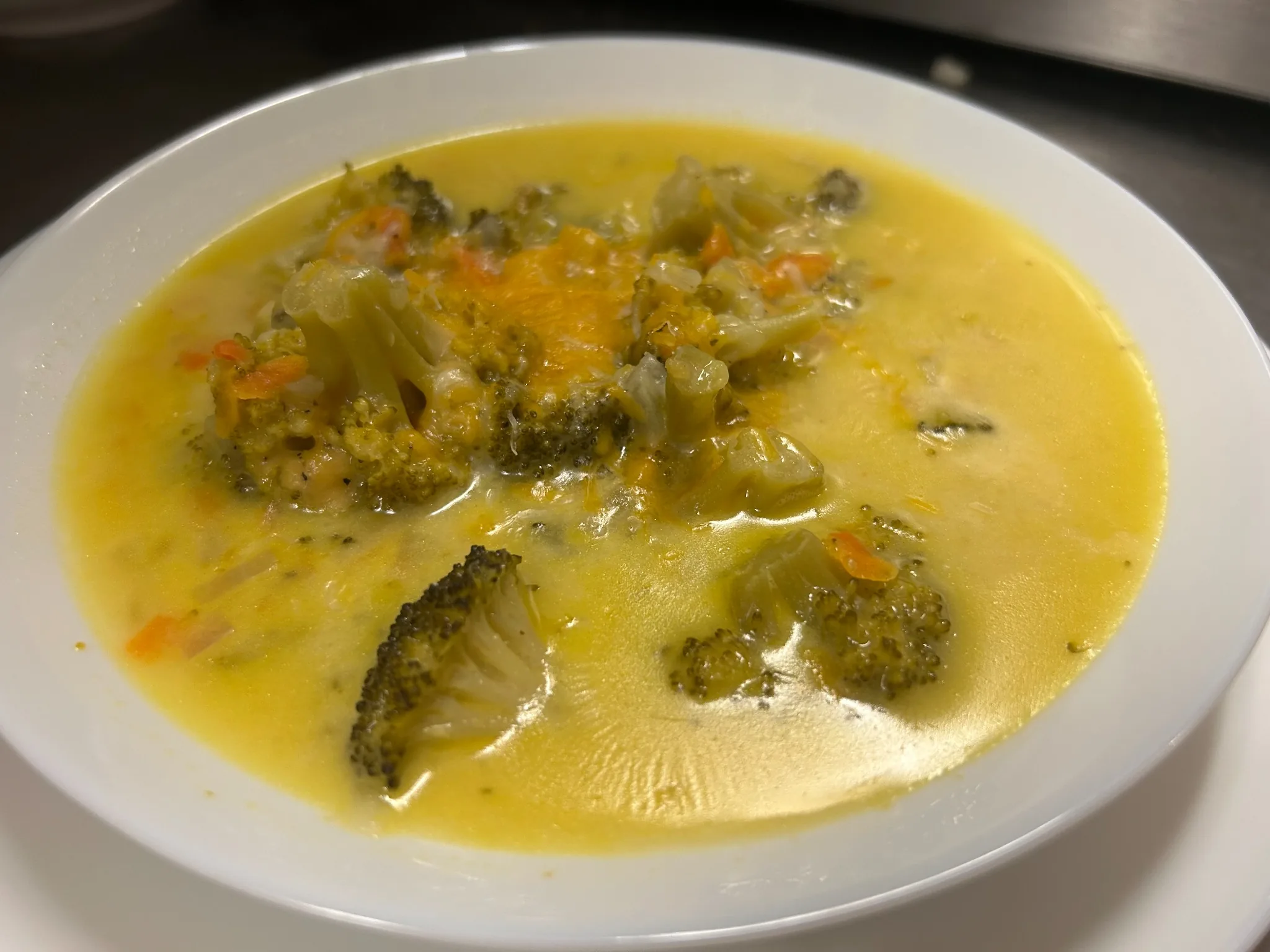 Creamy broccoli cheddar soup with broccoli florets and melted cheddar in a white bowl at Kat’s Café & Restaurant.
