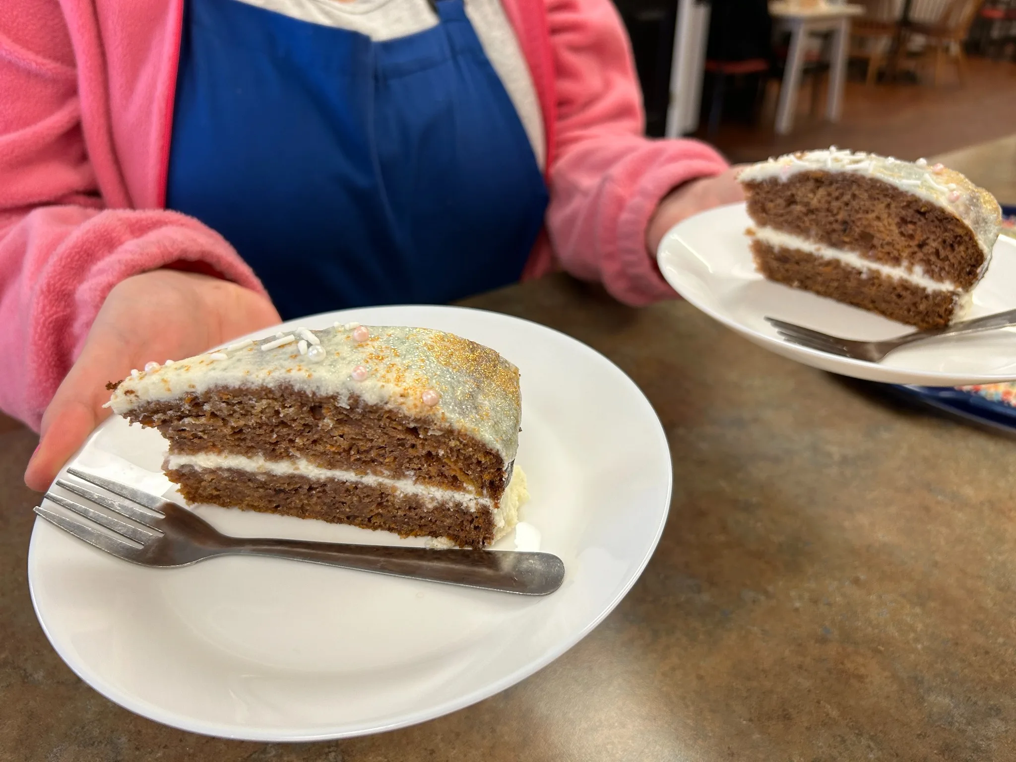 Slices of carrot cake with cream cheese filling and frosting being held on plates at Kat’s Café & Restaurant.