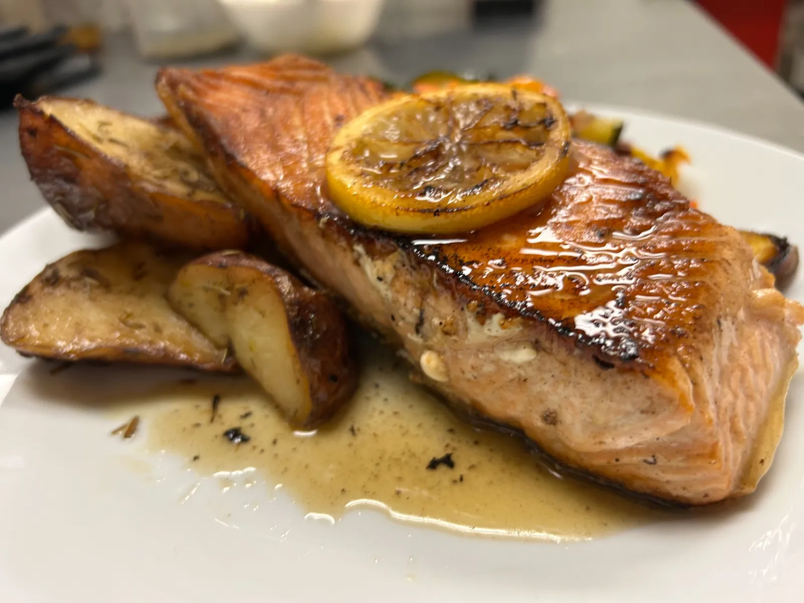 Cast-iron seared salmon fillet with potatoes, pan sauce, and a charred lemon slice at Kat’s Café & Restaurant.