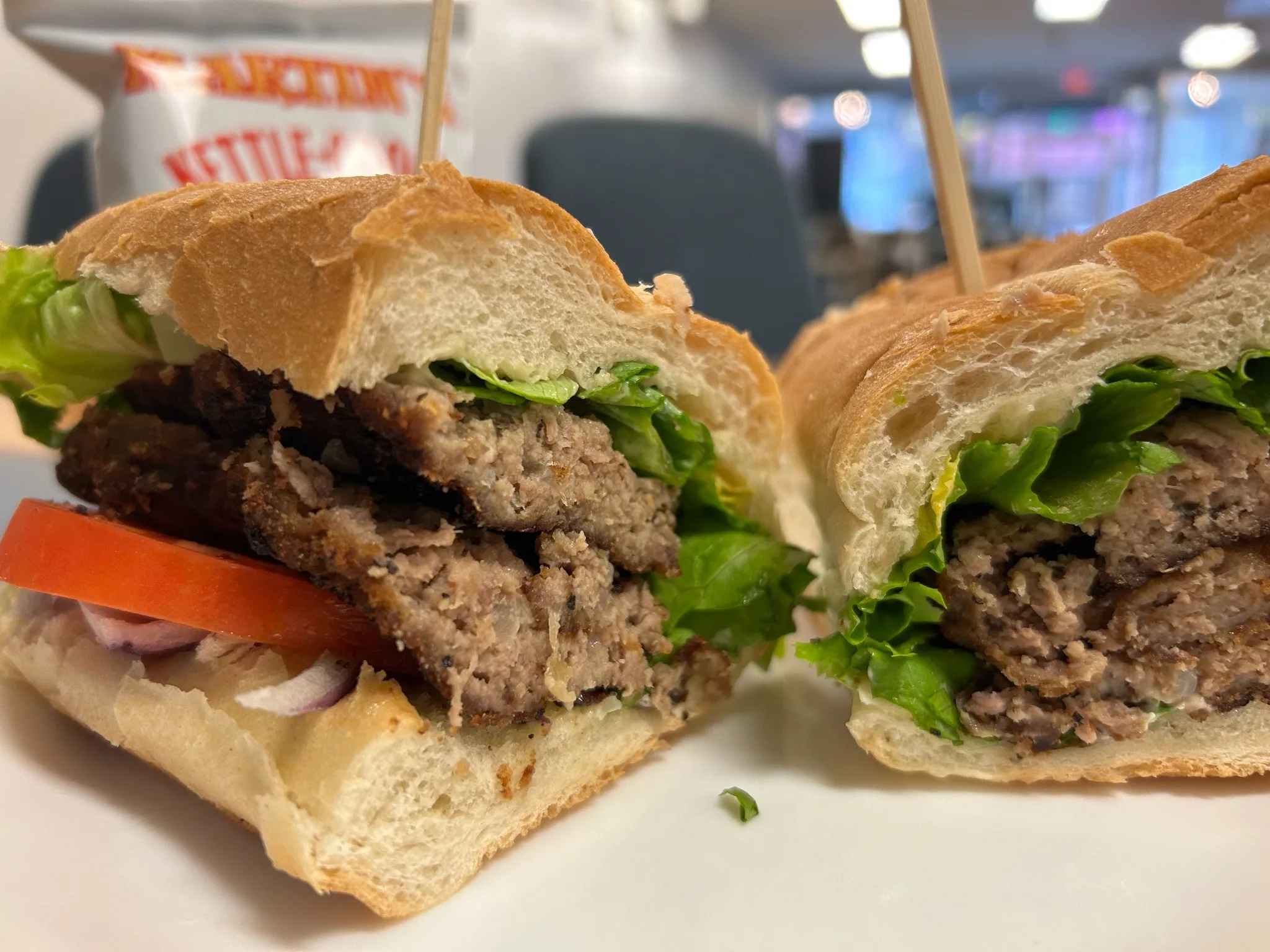 City chicken (minced meat kebabs) specialty sub cut in half, showing breaded city chicken with lettuce, tomato, and red onion on a long roll at Kat’s Café & Restaurant.