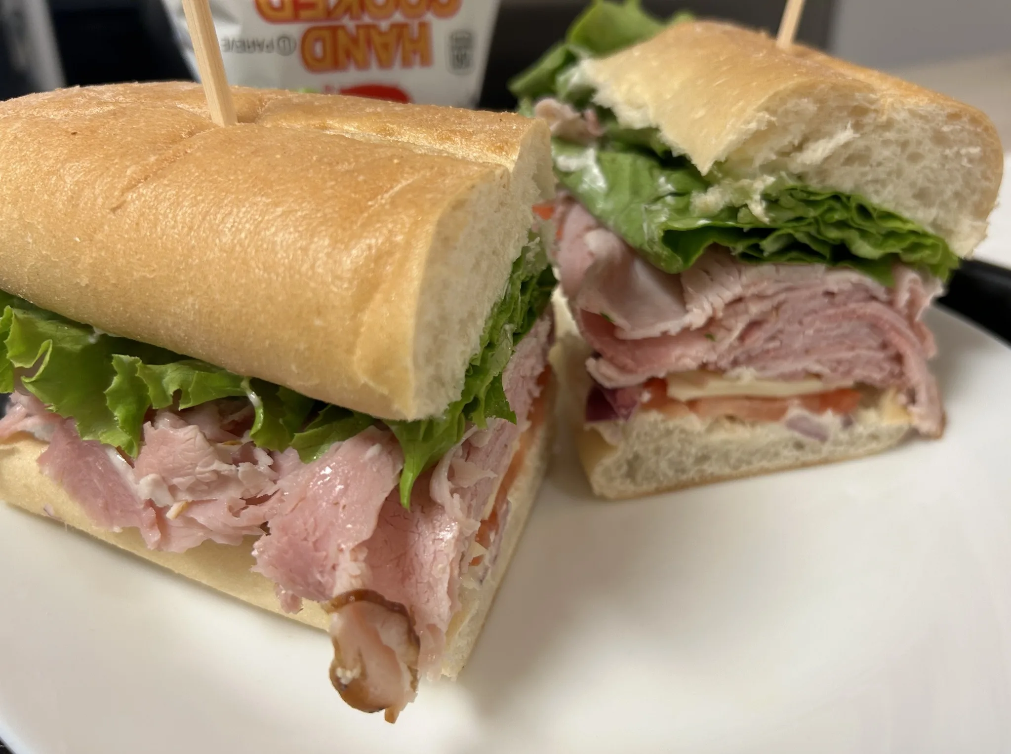 Country ham sub cut in half with sliced ham, cheese, lettuce, tomato, and red onion on a long roll at Kat’s Café & Restaurant.