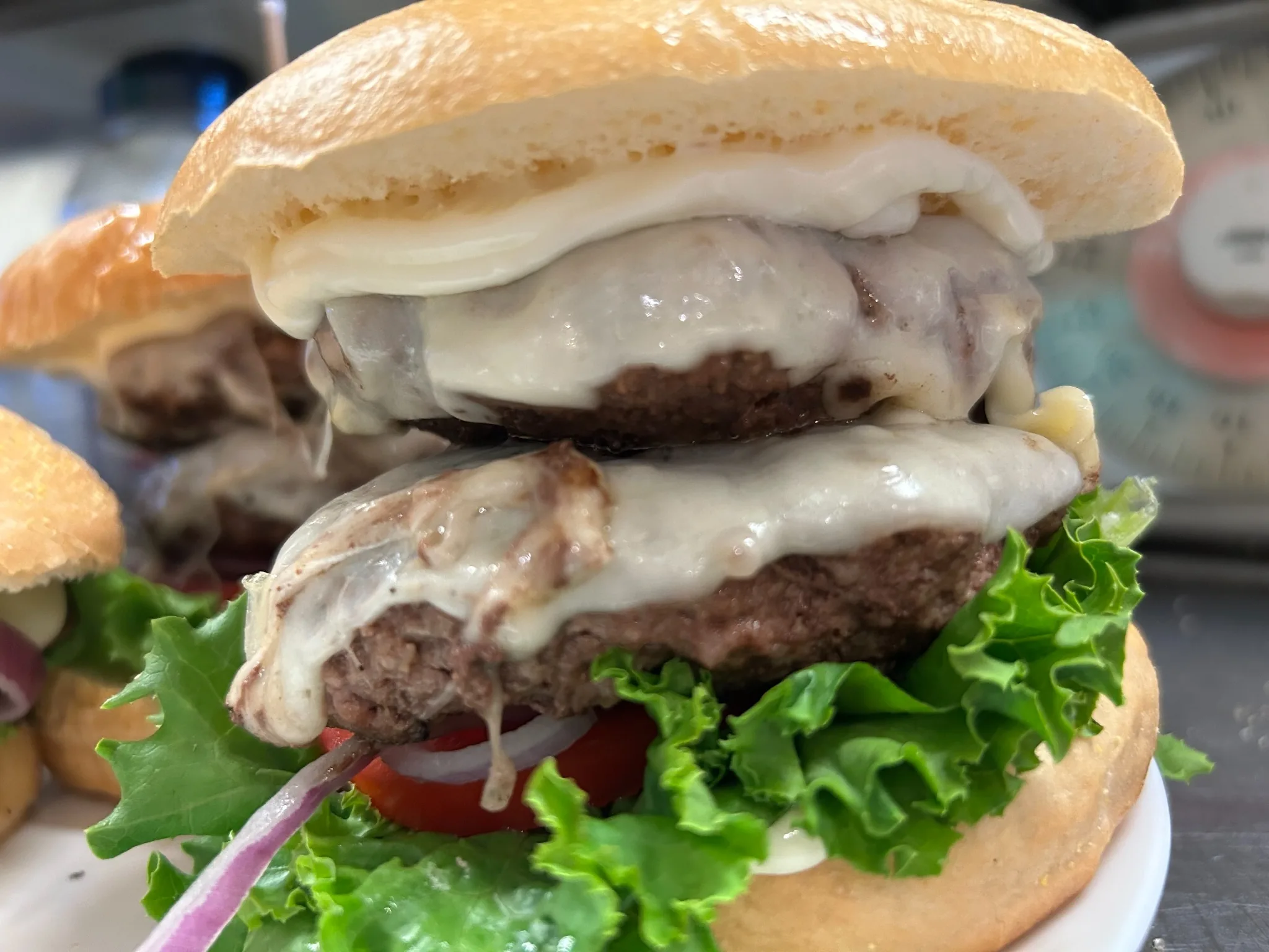 Double smash burger with two beef patties, melted cheese, lettuce, tomato, red onion, and creamy sauce on a bakery bun at Kat’s Café & Restaurant.